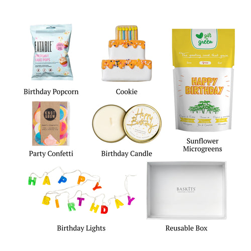 Flat lay of Happy Birthday! M, showing all 6 items included in the box, including the Knot & Bow Confetti,Happy Birthday Travel Candle and container.