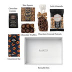 Flat lay of Chocolate Delight, showing all 6 items included in the box, including the Skor Square,Cinnamon Chocolate Barand White Gift Box with Clear Top.