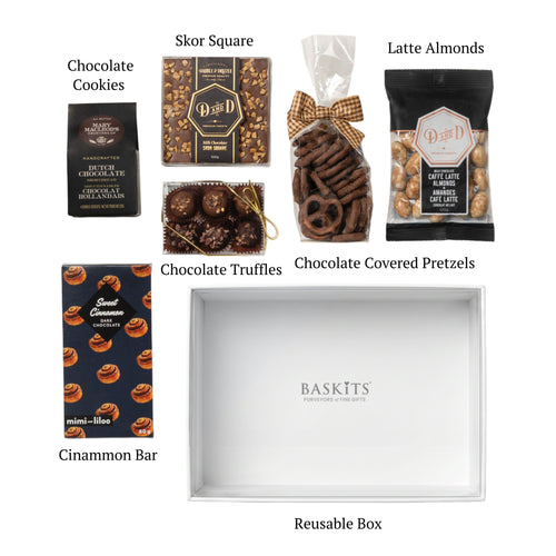 Flat lay of Chocolate Delight, showing all 6 items included in the box, including the Skor Square,Cinnamon Chocolate Barand White Gift Box with Clear Top.