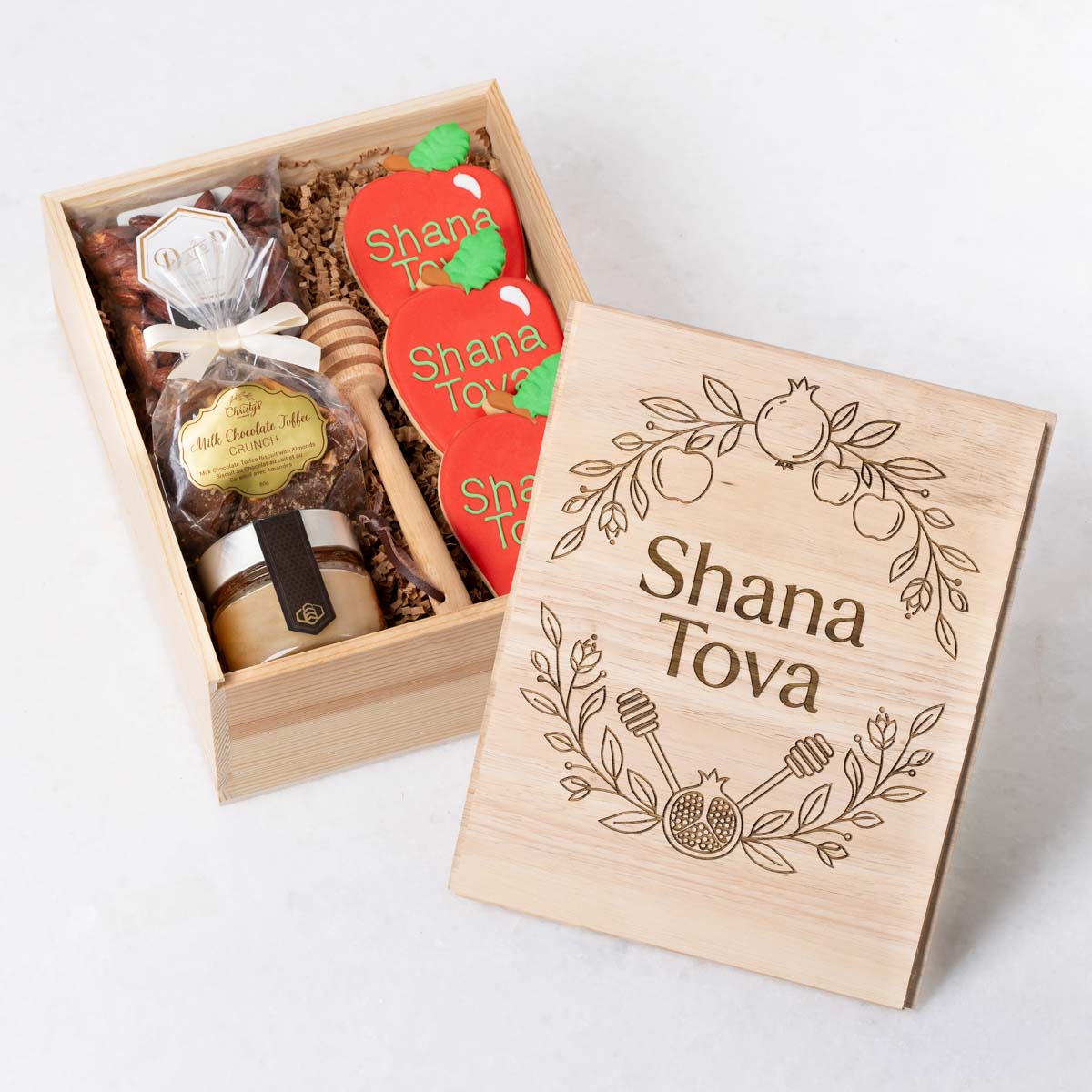 Rosh Hashanah gift basket with gourmet raw honey, hand-painted apple-shaped cookies, chocolate, and almond treats.