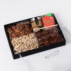 Rosh Hashanah gift basket containing gourmet raw honey, a hand-painted apple-shaped cookie, and various nut treats.