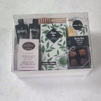 Hands unpacking a 7-piece Just Tea & Me gift box, displaying Mary Macleod's famous Chocolate Crunch Cookies, and an array of essential comforting indulgences. 