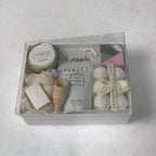 Hands unpacking a 10-piece Just Because gift box, displaying our Lavender Bath Bombs, and an array of essential spa items.